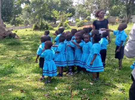 Head Start pupils in blue uniforms gathered outside with their teacher